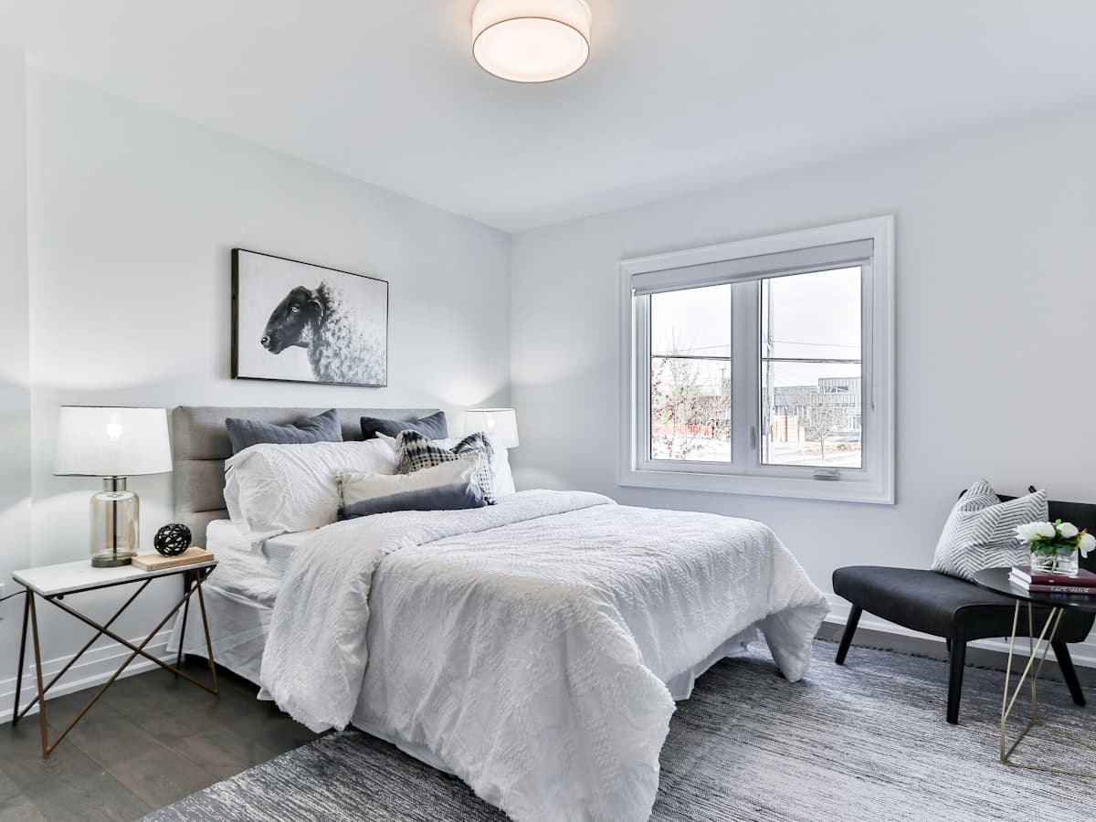 Fluffy white comforter draped over a bed in a bright minimal bedroom