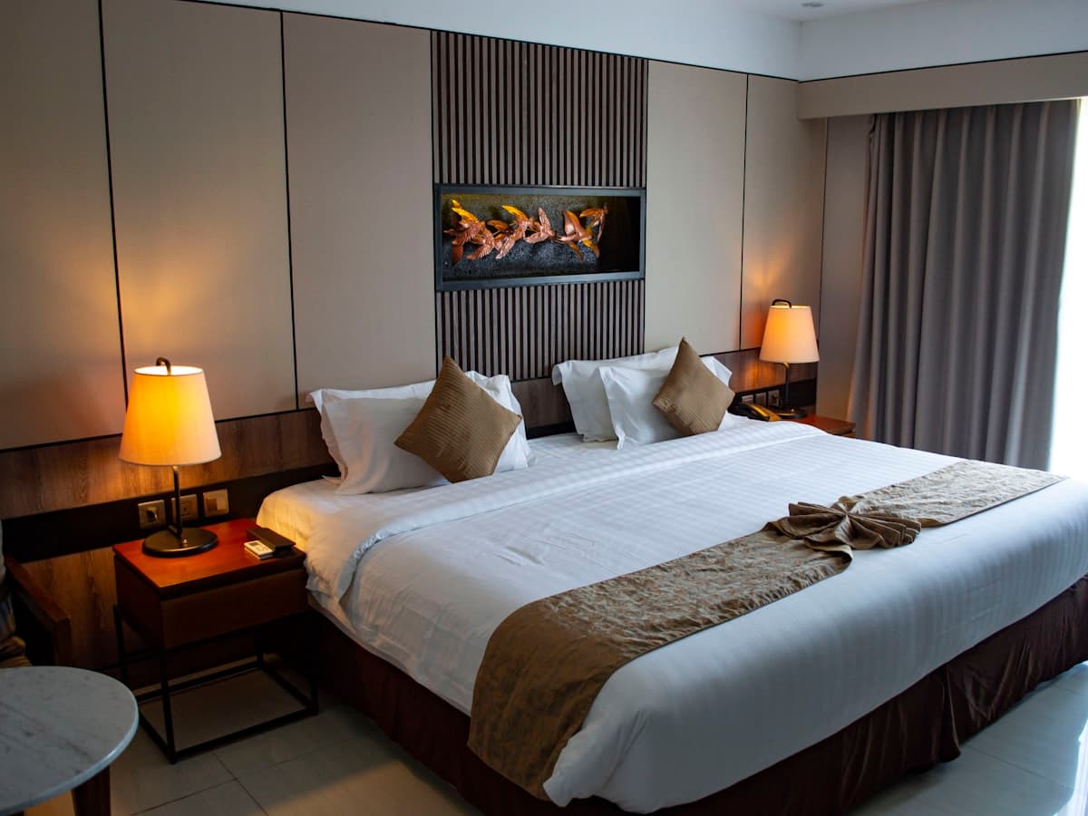 Neatly dressed hotel bed with a tailored mattress cover and runner