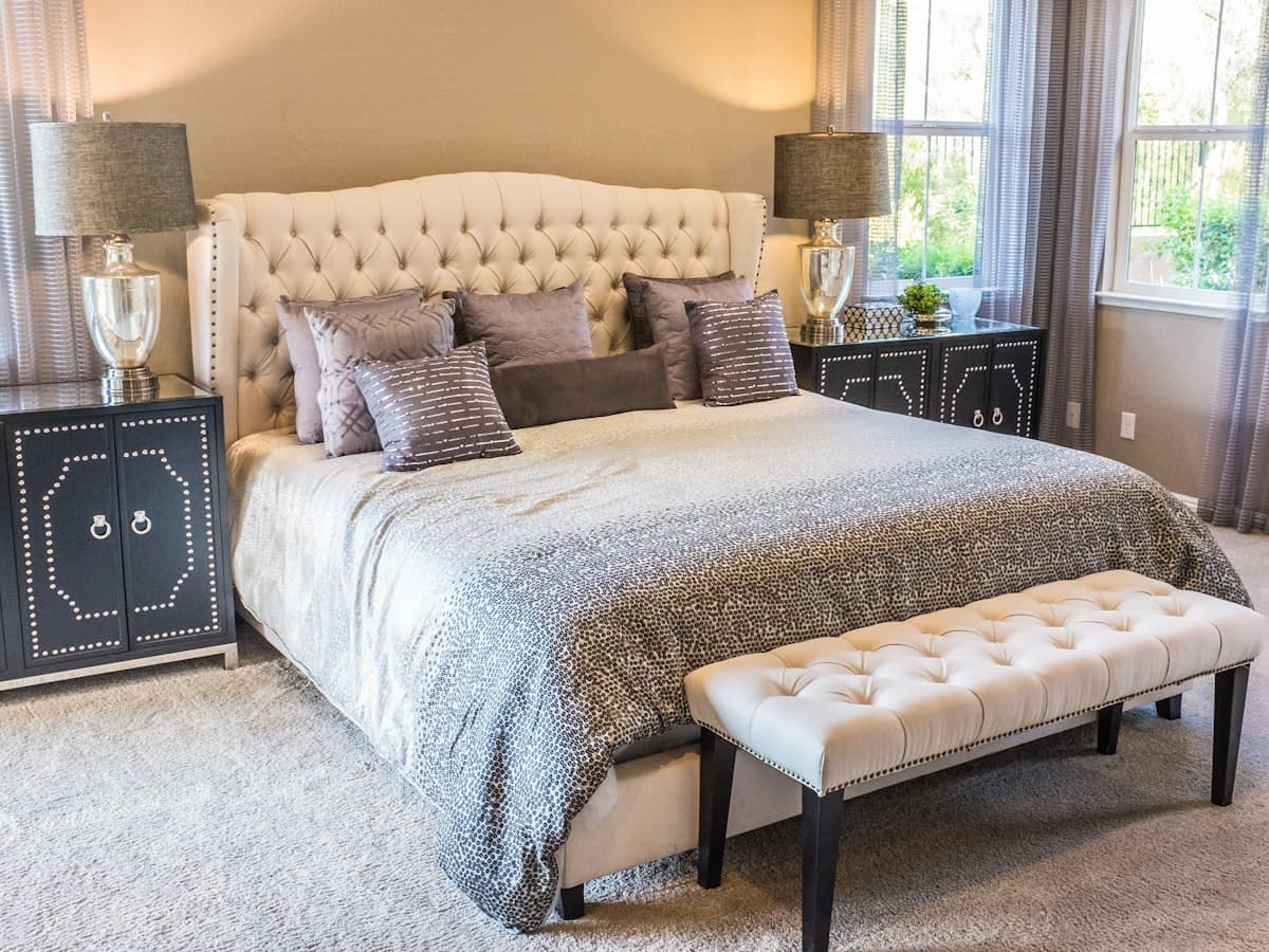 Layered decorative pillows with premium covers on an upholstered bed